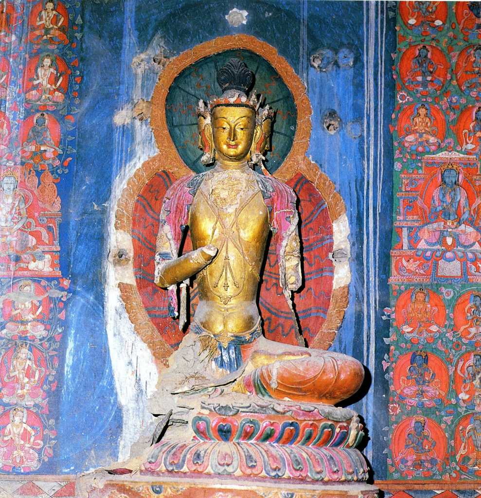 Tibet Guge 06 Tsaparang White Temple 08 04 Vairocana 1 There are six statues of a three-headed Vairocana, three on the left, three on the right, which together form a meditation cycle of Vairocana. Originally they were each enclosed in a richly decorated stucco frame (torana), an arch, usually depicting foliage and animate designs above the divinity's head. Small holes in the wall secured them around the images. Notice especially the thin, elongated torsos, the elongated faces, distinctive stomach cleavage, slight abdominal bulge, and extremely slender waists are all characteristic of Kashmiri art. Photo of second Vairocana - Weyer/Aschoff: Tsaparang, Tibets Grosses Geheimnis.